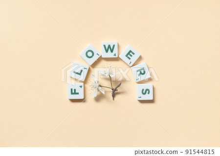 Scrabble tiles with spring flowers on beige background. 91544815