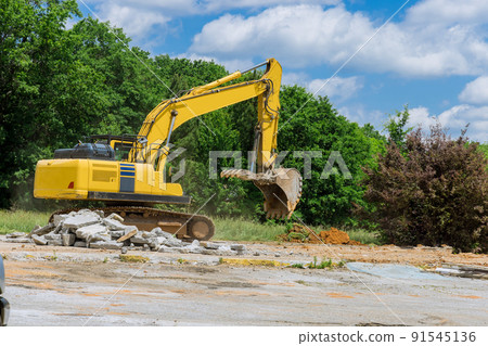 An excavator chops and crumbles old concrete crusher for concrete slabs on construction site An excavator chops and crumbles old concrete crusher for concrete slabs on construction site 91545136