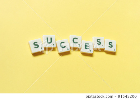 Success formed of scrabble blocks on yellow background. 91545200