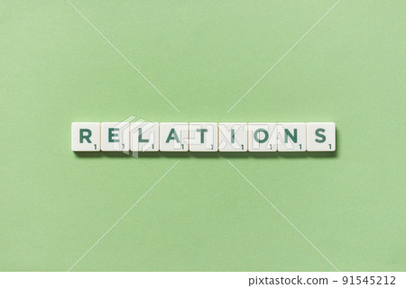 Relations formed of scrabble blocks on green background. 91545212