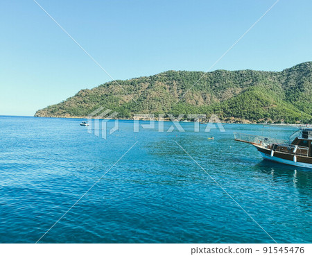 sea coast. blue waves of sea water with white foam. the sea at the foot of the mountain with plants and trees at the top. holidays in a hot country sea coast. blue waves of sea water with white foam. the sea at the foot of the mountain with plants and trees at the top. holidays in a hot country 91545476
