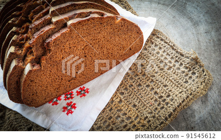 Fresh rye sliced bread, natural linen napkin and white serviette with cross-stitch on rustic wooden background Fresh rye sliced bread, natural linen napkin and white serviette with cross-stitch on rustic wooden background 91545612