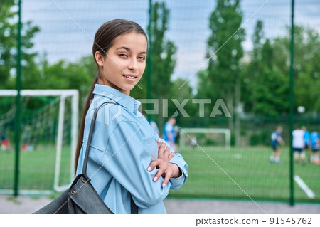 Portrait of teenage female student looking at camera, school stadium background 91545762