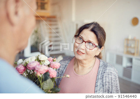 Smiling charming senior lady in eyeglasses receiving tender bouquet from husband on Valentines day 91546440