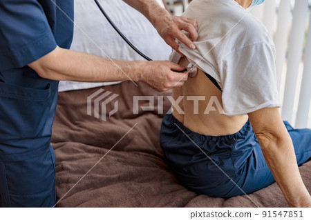 Close up of doctor listening to old woman's patient breathing, using stethoscope 91547851