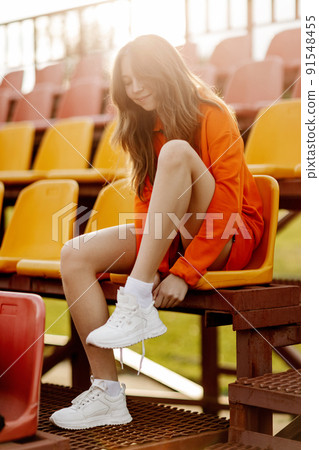 A teenage girl ties her shoelaces in sneakers, prepares for training 91548455