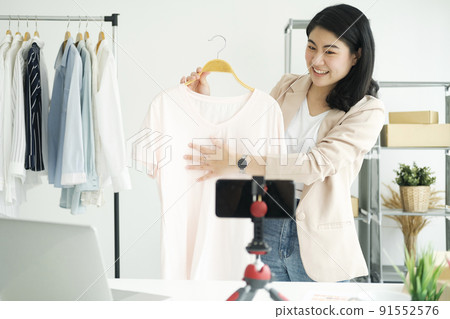 Businesswoman giving important pieces of advice while streaming video for women's clothing. Businesswoman giving important pieces of advice while streaming video for women's clothing. 91552576