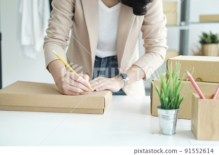 Start up small business owner writing address on cardboard box a. 91552614