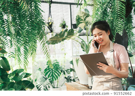Young  woman plant shop owner is checking customer order from website 91552662