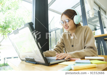 Young female college student uses a computer to access the Internet for online learning. Young female college student uses a computer to access the Internet for online learning. 91552666