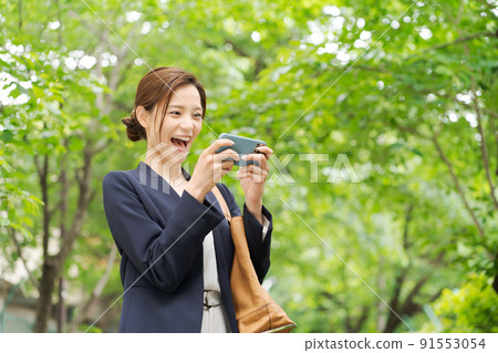 A woman with a smartphone, fresh green 91553054