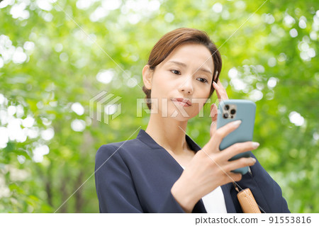 一個有智能手機的女人,新鮮的綠色 一個有智能手機的女人,新鮮的綠色 91553816