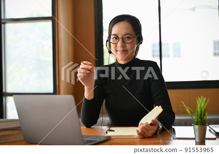 Cheerful young asian female freelance online tutor wearing a headset Cheerful young asian female freelance online tutor wearing a headset 91553965