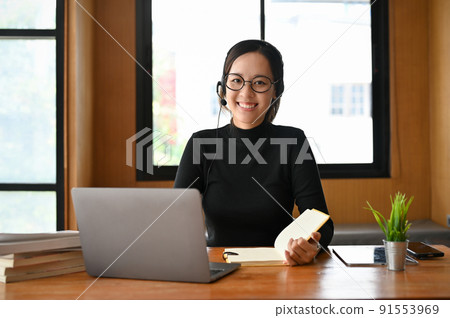 Beautiful young Asian female freelance tutor with eyeglasses and headset Beautiful young Asian female freelance tutor with eyeglasses and headset 91553969