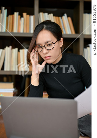 Female journalist focused reading and working on laptop Female journalist focused reading and working on laptop 91553979