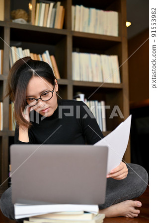 Focused young asian female freelancer or writer concentrated reading some content on laptop Focused young asian female freelancer or writer concentrated reading some content on laptop 91553982