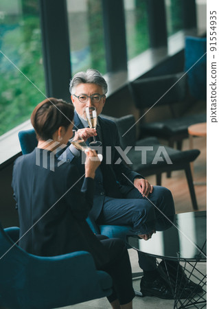 Senior manager and secretary drinking champagne in the lounge Senior manager and secretary drinking champagne in the lounge 91554935