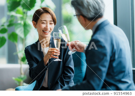 Senior manager and secretary drinking champagne in the lounge 91554963