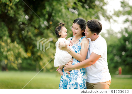 Happy Asian family father, mother, and little child daughter playing in the park enjoying the beautiful nature at sunset, Happy family holidays concept. 91555623