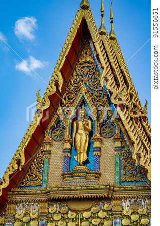 Buddha statue stands on the front of the temple building with beautiful Thai Art pattern style in the open sky day. 91556651