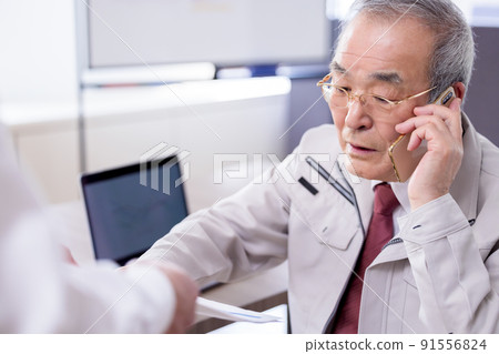 A busy senior man reading documents while talking on a business smartphone 91556824