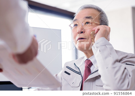 A busy senior man reading documents while talking on a business smartphone A busy senior man reading documents while talking on a business smartphone 91556864