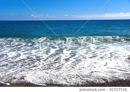 White waves crashing against the coast on a clear day White waves crashing against the coast on a clear day 91557550