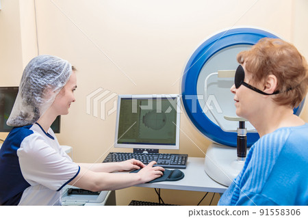 A girl optometrist examines the eyes of a patient using special modern equipment A girl optometrist examines the eyes of a patient using special modern equipment 91558306