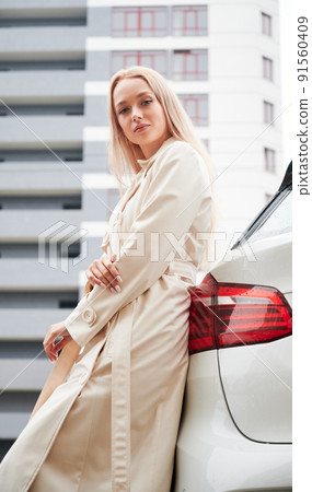 Portrait of beautiful young woman posing near her modern white car outdoor. Portrait of beautiful young woman posing near her modern white car outdoor. 91560409