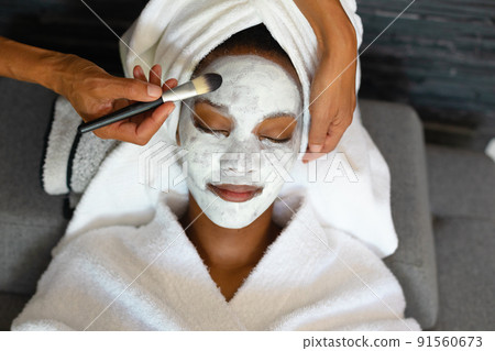 Young african american woman getting face cream applied at home 91560673