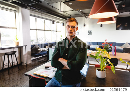 Portrait of confident young caucasian businessman with arms crossed in creative office Portrait of confident young caucasian businessman with arms crossed in creative office 91561479
