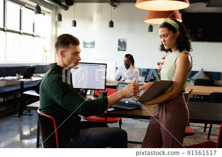 Multiracial businessman and businesswoman discussing over file in creative office 91561517