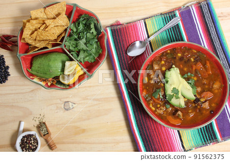 Fresh Bowl of Tortilla Soup on Wooden Table With Avocado and Cilantro Fresh Bowl of Tortilla Soup on Wooden Table With Avocado and Cilantro 91562375