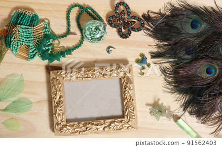 Green Jewelry and Peacock Feathers With Gold Picture Frame on Wooden Table 91562403