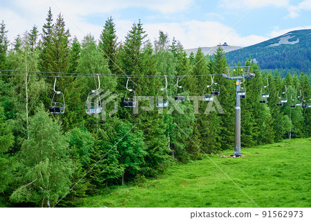 Open cable car line. Karpacz resort in Poland with lift road. Chairlift against green forest trees. Family outdoor recreation in mountains 91562973