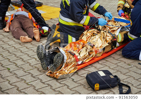 Rescuers provide first aid to the victim during a car accident. Person injured in the accident is lying on the road 91563050