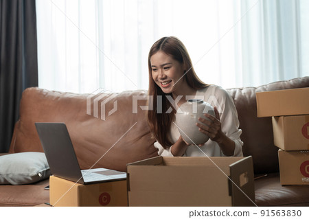 A female entrepreneur selling ceramic jar via live streaming laptop computer and checking orders from customer for online shopping concept A female entrepreneur selling ceramic jar via live streaming laptop computer and checking orders from customer for online shopping concept 91563830