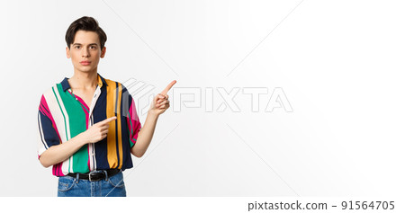 Portrait of young handsome man pointing fingers at upper right corner, showing logo, standing over white background Portrait of young handsome man pointing fingers at upper right corner, showing logo, standing over white background 91564705