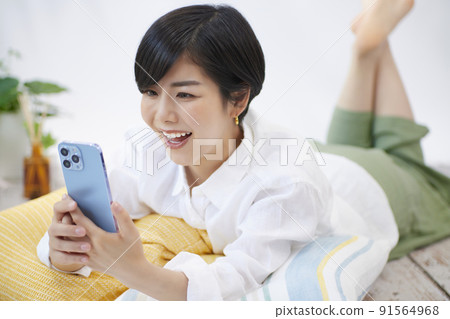 Young woman looking at her smartphone in the living room Young woman looking at her smartphone in the living room 91564968