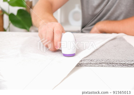 man removes fabric pills using lint shaver. man removes fabric pills using lint shaver. 91565013