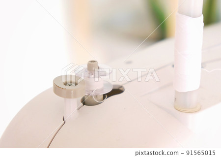 Winding threads on a bobbin on sewing machine. Winding threads on a bobbin on sewing machine. 91565015