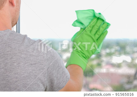 A man washes a glass window and plastic frame with A man washes a glass window and plastic frame with 91565016
