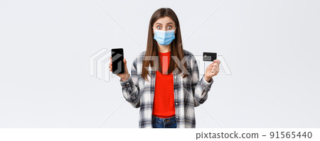 Coronavirus outbreak, working from home, online shopping and contactless payment concept. Excited woman in medical mask showing credit card and mobile phone, look surprised Coronavirus outbreak, working from home, online shopping and contactless payment concept. Excited woman in medical mask showing credit card and mobile phone, look surprised 91565440