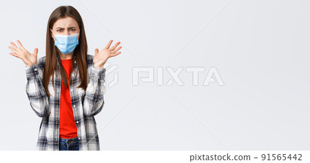 Different emotions, covid-19 pandemic, coronavirus self-quarantine and social distancing concept. Angry, outraged woman in medical mask, arguing, look mad, raise hands in dismay, complaining Different emotions, covid-19 pandemic, coronavirus self-quarantine and social distancing concept. Angry, outraged woman in medical mask, arguing, look mad, raise hands in dismay, complaining 91565442