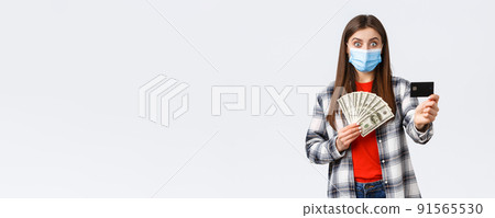 Money transfer, investment, covid-19 pandemic and working from home concept. Surprised young woman showing credit card and holding her cash savings, make bank account to save-up for trip Money transfer, investment, covid-19 pandemic and working from home concept. Surprised young woman showing credit card and holding her cash savings, make bank account to save-up for trip 91565530