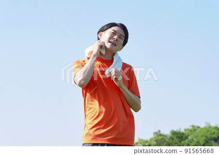 A man exercising to wipe sweat outside 91565668