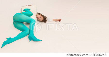 Studio shot of young sad girl in bright cyanic tights posing with mirror isolated over white background. Vivid style, beauty, queer, freak, fashion concept. 91566243