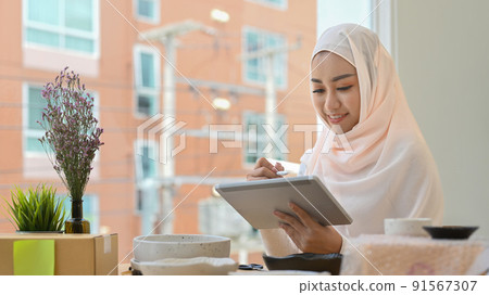 Muslim woman business owner checking product purchase order on digital tablet. Online selling, e-commerce concept 91567307