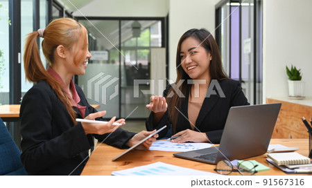 Two happy business colleagues discussing business project, working together in office 91567316