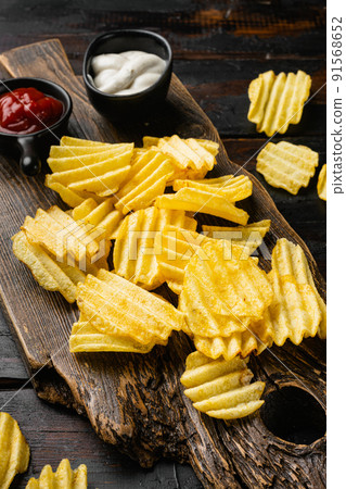 Wavy Salt  Pepper Flavored Potato Chips on old dark  wooden table background 91568652